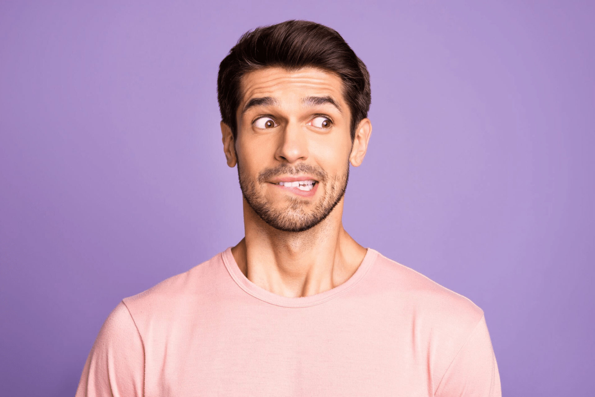 Young man showing an uneven front tooth against a purple background